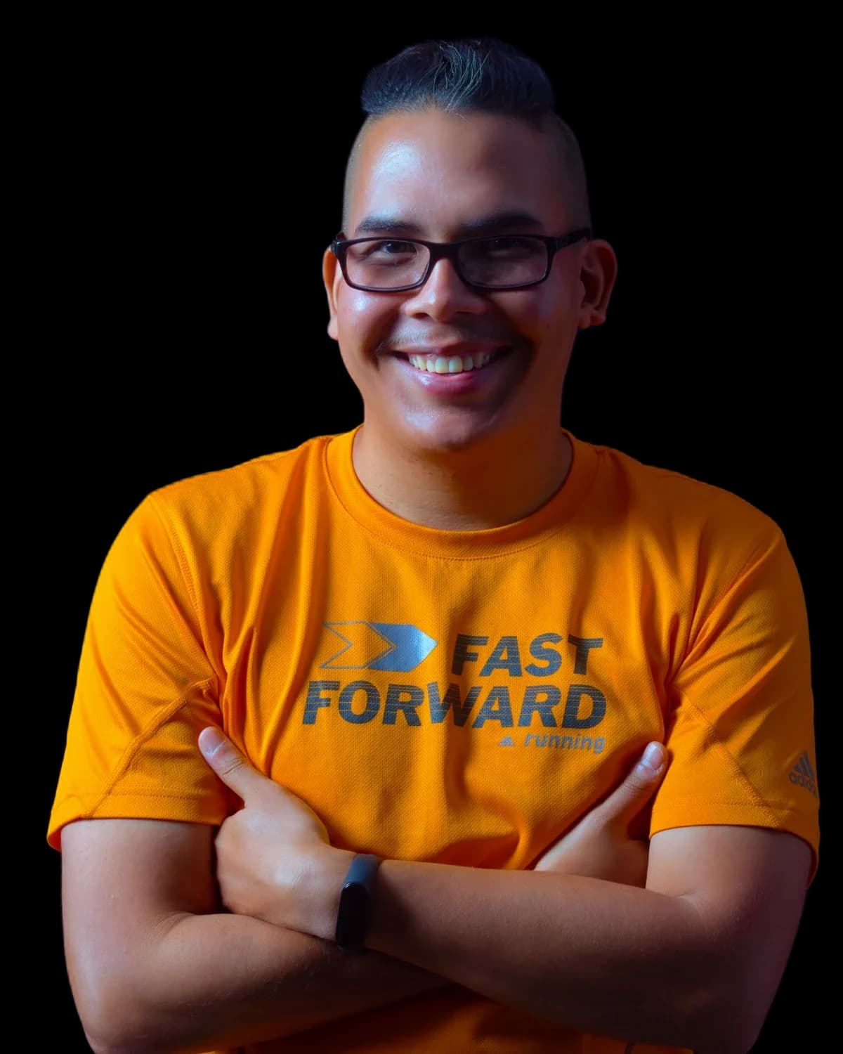Portrait of Noelsajor, smiling with his arms crossed, in an orange running shirt against a dark background